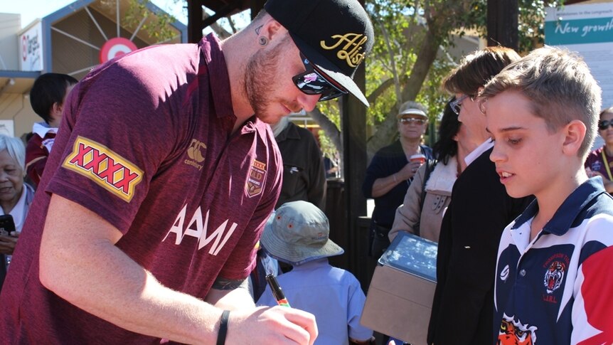 Queensland forward Chris McQueen signs an autograph during the Maroons fan day in Longreach.