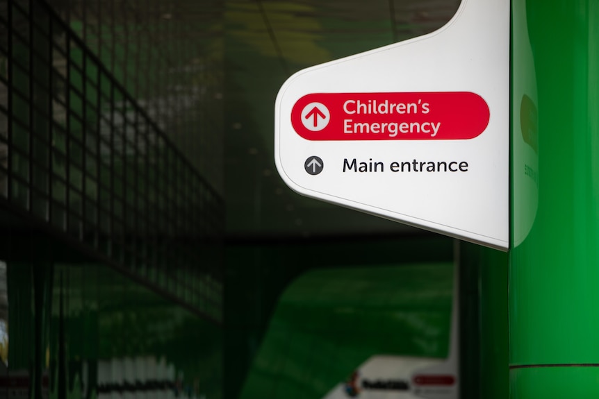 A sign with the words "Children's Emergency" and "Main entrance" against a shadowy background.
