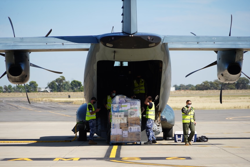 Pallets are loaded into the back of a large green aeroplane