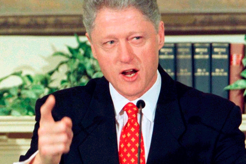 Bill Clinton points his finger as he speaks at a podium.