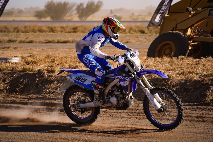 A dirt bike rider races through the desert.