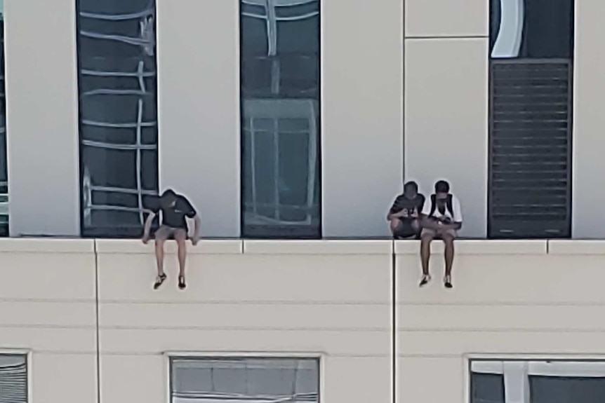 Two people sit on ledge of building