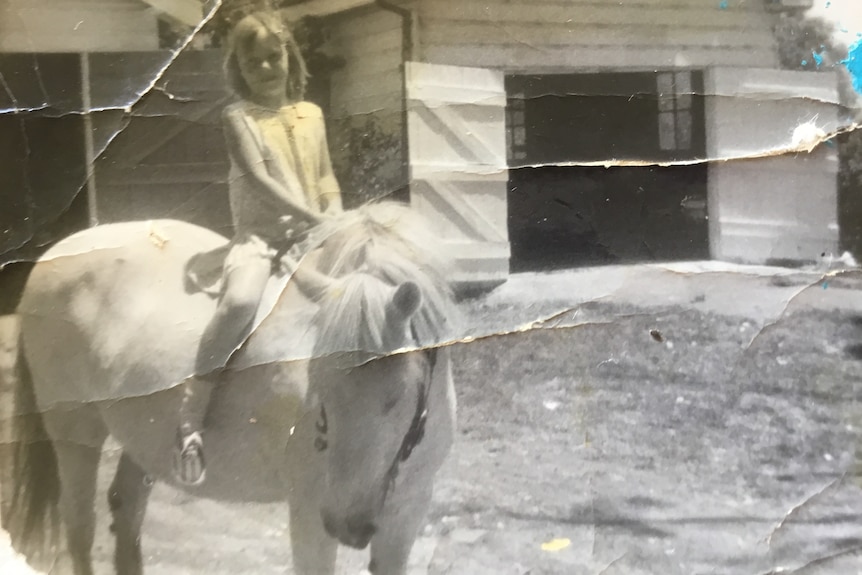 black and white photo of a young girl on a pony.