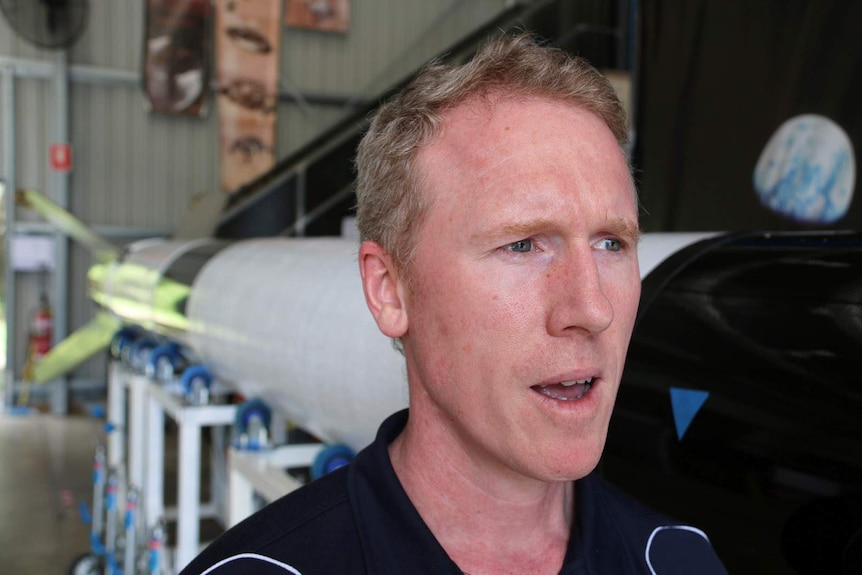 A man speaking alongside a nine-metre suborbital rocket