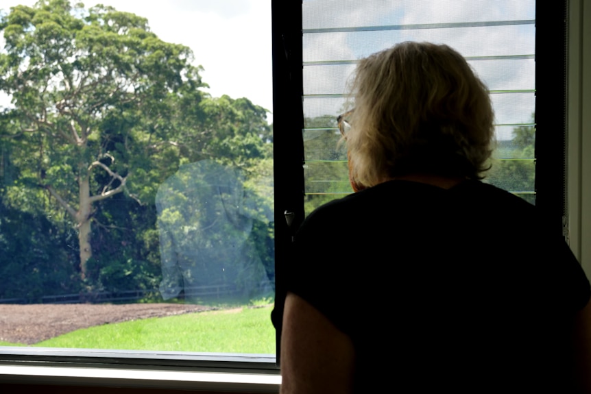 Woman looks out the window to greenery