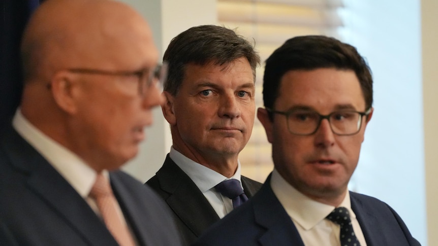 Three men in suits, looking serious.