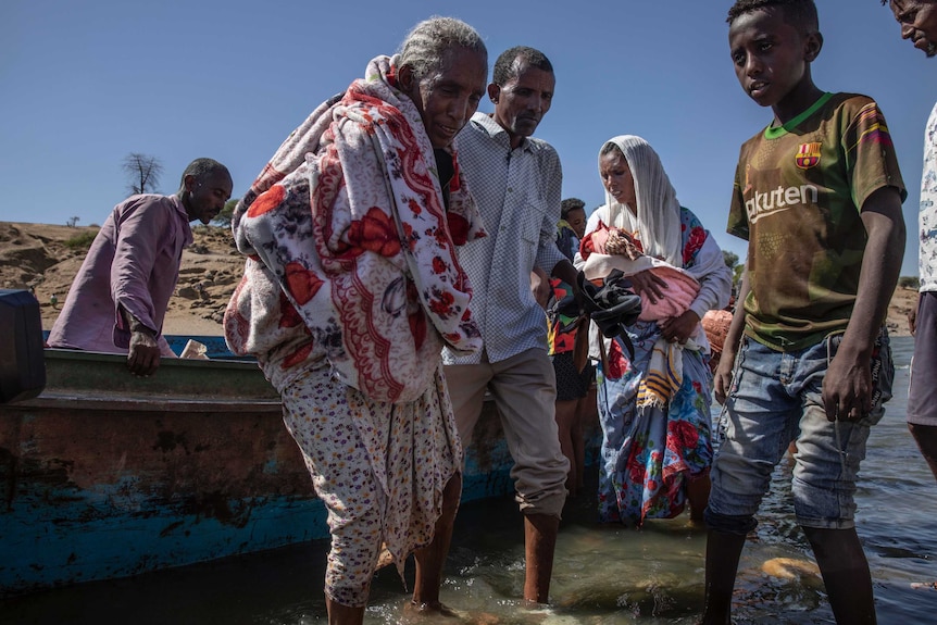 Tigray refugees who fled the conflict get off a boat in Sudan