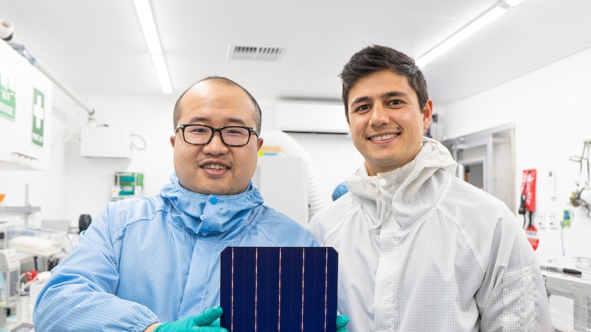 David Hu and Vince Allen wear protective suits and hold a solar cell.