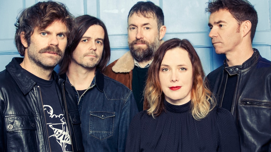 Five members of Slowdive stand in a line and look at the camera