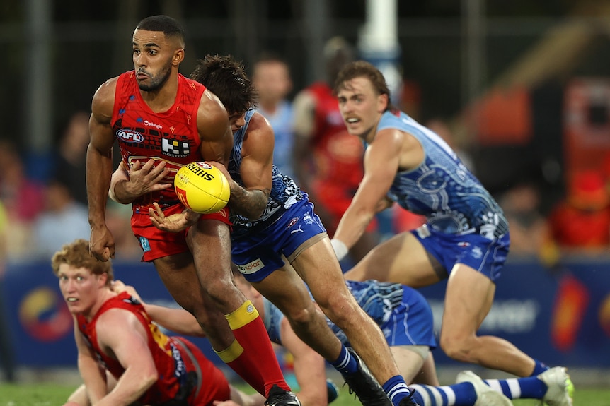 A Gold Coast AFL player is tackled while running with the ball