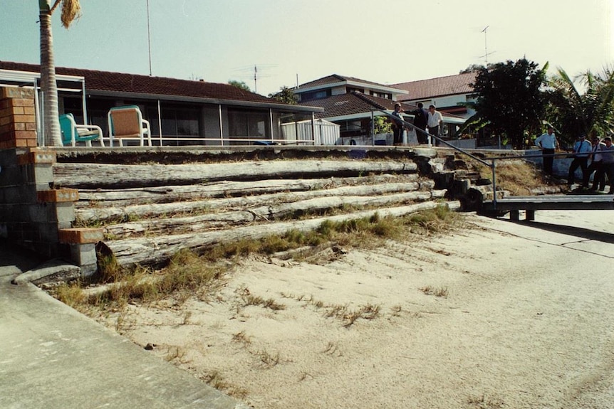 a wooden log wall in front of a house, police in background