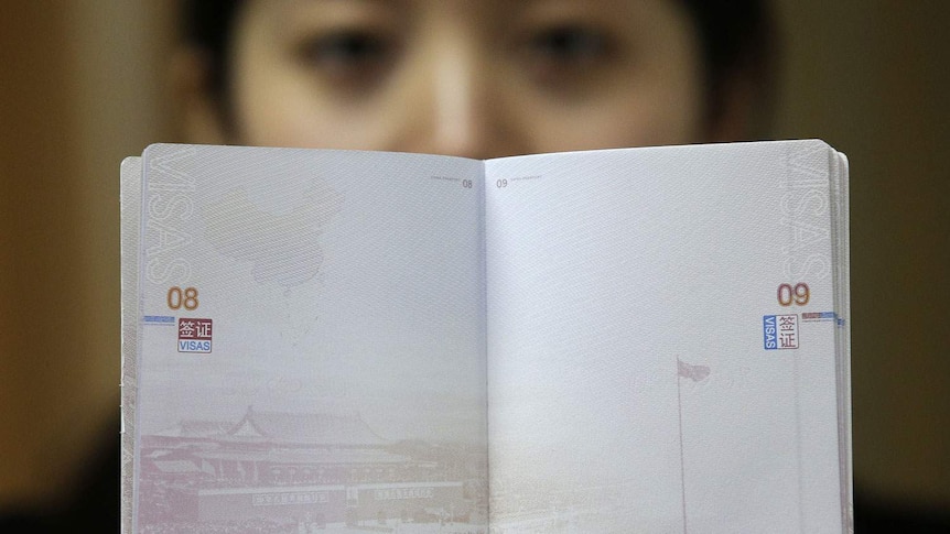 A woman holds up a blank passport page. 