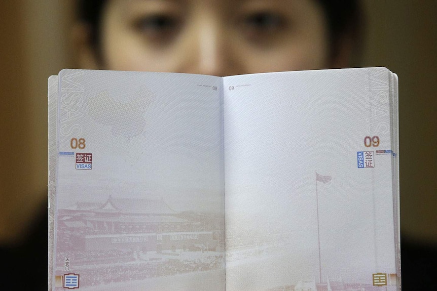 一名女子手持中国护照。