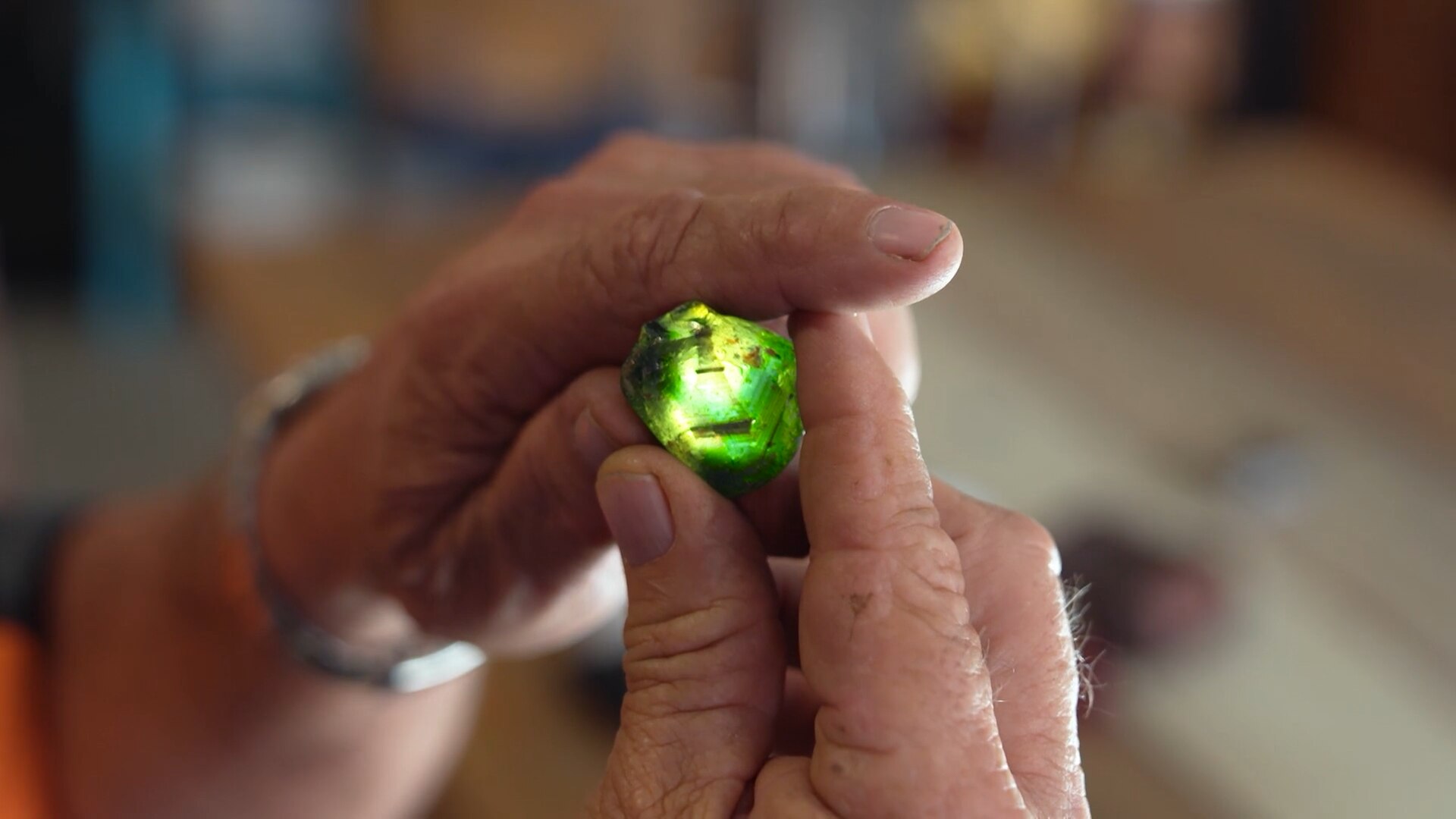 Close up of man holding uncut green gem the size of aa 50-cent piece