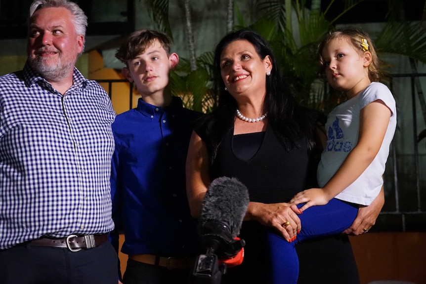 A family of four stands in front of a crowd.