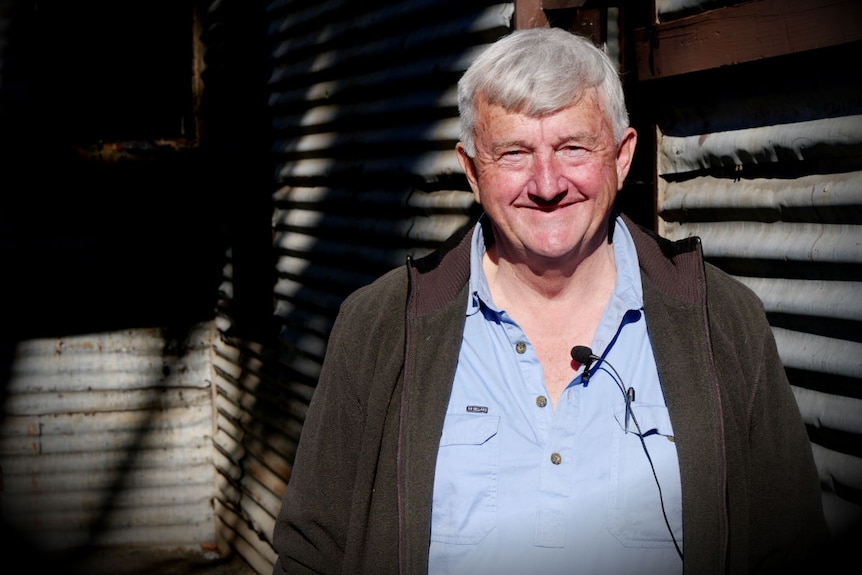 Peter McCarthy who worked in the mining industry for 50 years stands in front of an old corrugated building.