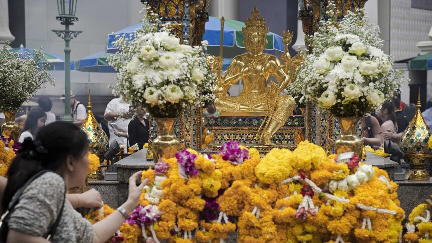A woman lays a flower garland at the Erawan shrine in central Bangkok