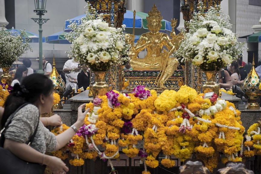 A woman lays a flower garland at the Erawan shrine in central Bangkok