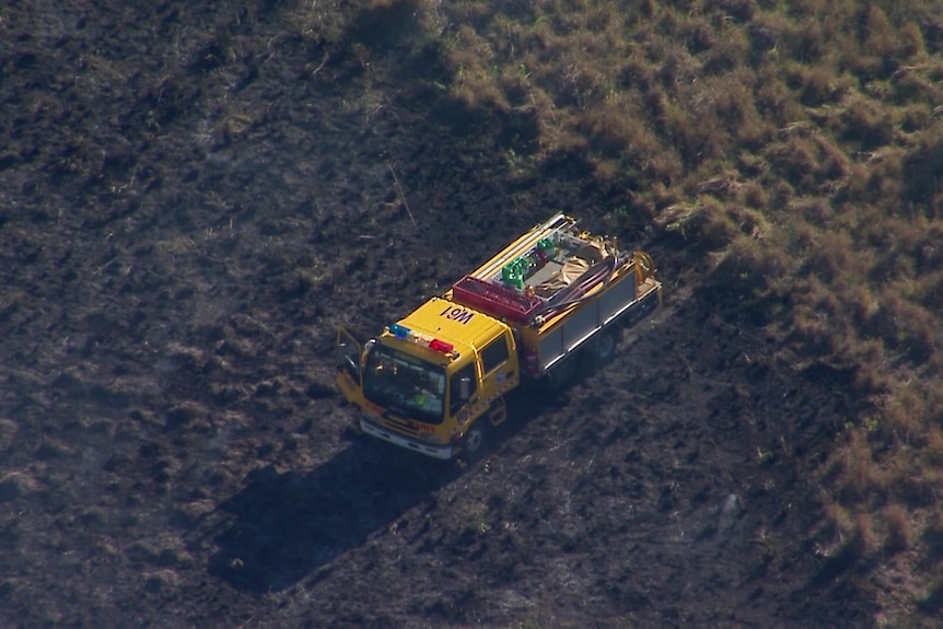 A fire truck stopped on scorched earth