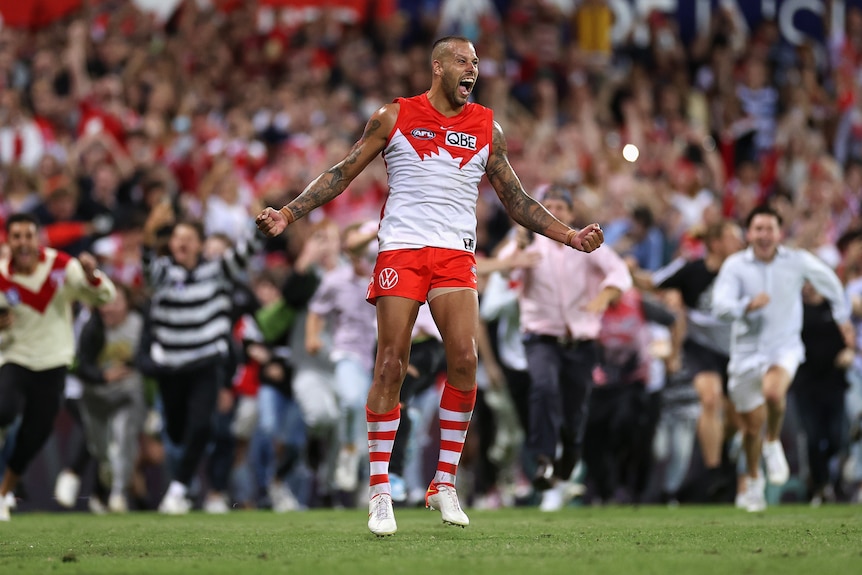Lance Franklin holds his arms out and yells in delight as fans start running toward him