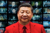 A close up of Xi Jinping in front of a screen of televisions with various faces and events from his rule. 