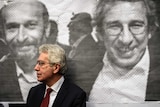 A man stands in front of a poster of Can Dundar and Erdem Gul.