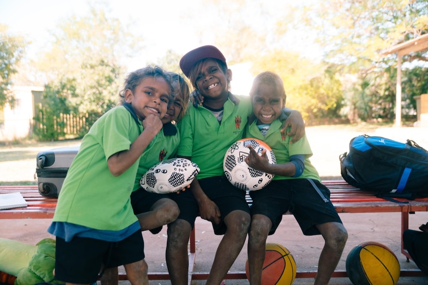 indigenous children smiling holding sports balls