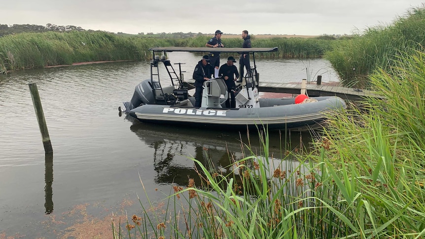 Police officers in an inflatable boat on a river with reeds