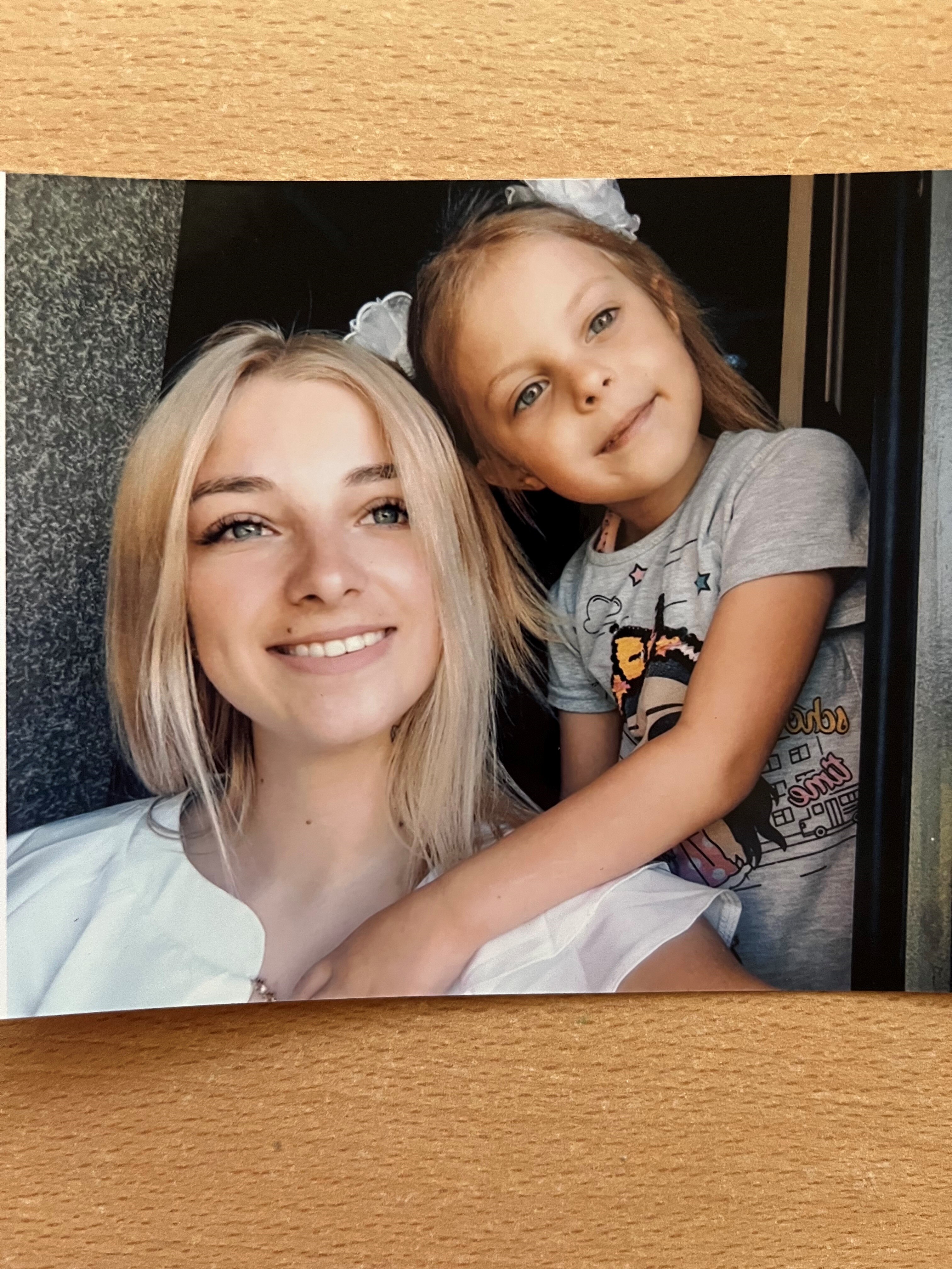 A young woman and her daughter in a close-up printed photo, smiling. 