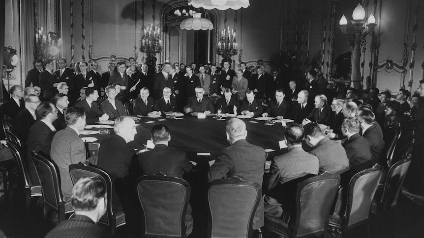 World leaders seated at round table discussing the fate of homeless victims of WW2