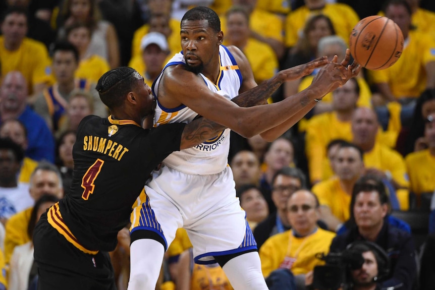 Cavaliers guard Iman Shumpert (L) attempts to knock the ball away from Warriors forward Kevin Durant.