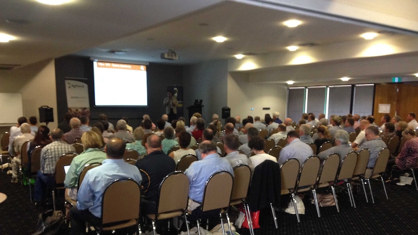 A crowd of people listen to a speaker a live export forum.