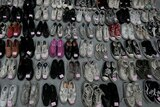 About 50 crumbled shoes in neat rows including converse, vans and a pair of pink slippers