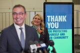 A sign saying thank you for being vaccinated stands behind a man and woman smiling