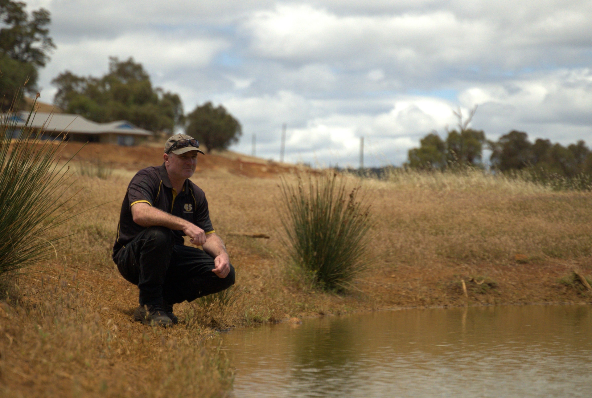 Tierra roja y una línea clara donde comienza el matorral y la vegetación, una mina al fondo.