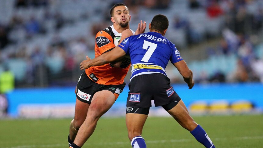 Josh Aloiai of the Tigers is tackled by Moses Mbye of the Bulldogs
