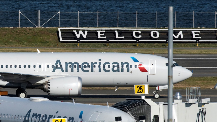 An American Airlines jet lands in front of a 'welcome' sign at LaGuardia airport in New York