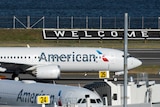 An American Airlines jet lands in front of a 'welcome' sign at LaGuardia airport in New York