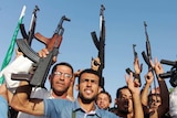 Iraqi tribal fighters shout slogans while holding weapons in Basra.