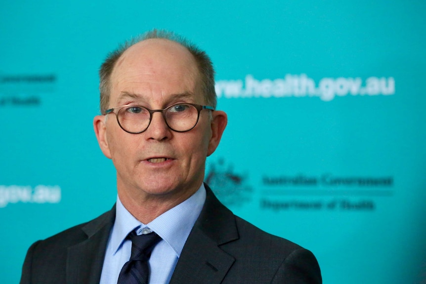 Paul Kelly stands in front of a blue wall with health.gov.au written on it