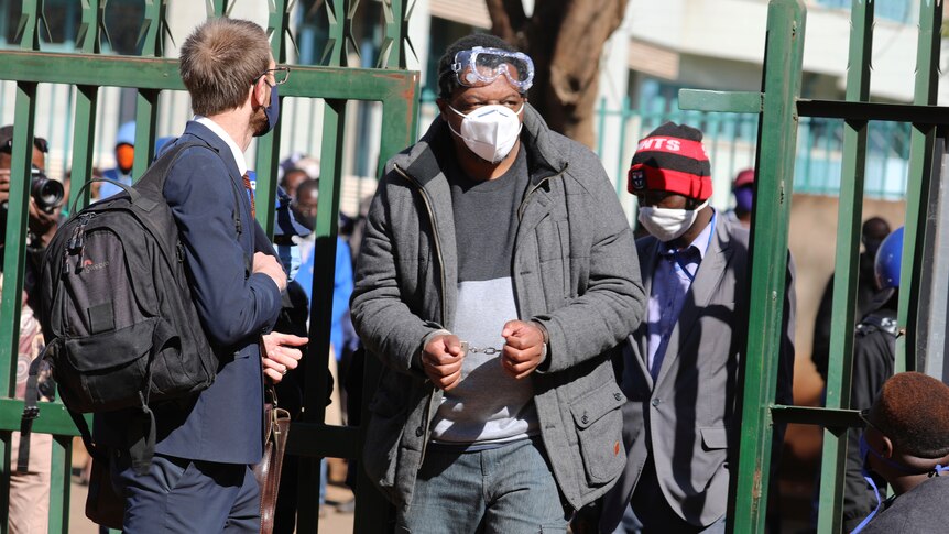 A man standing outside wearing handcuffs