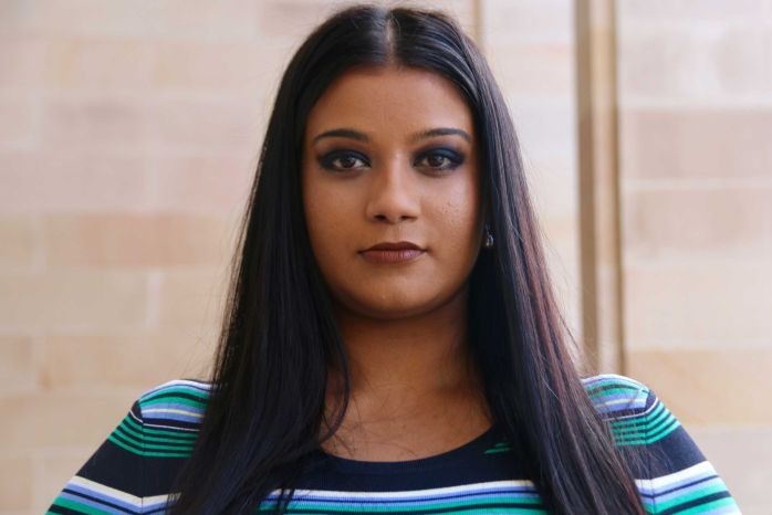 Woman with long dark hair and green-and-blue-striped top looking directly at the camera.