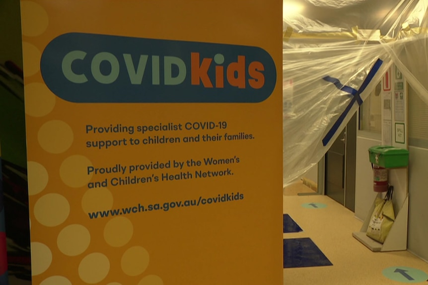 A sign saying COVIDKIDS with a ward under construction behind