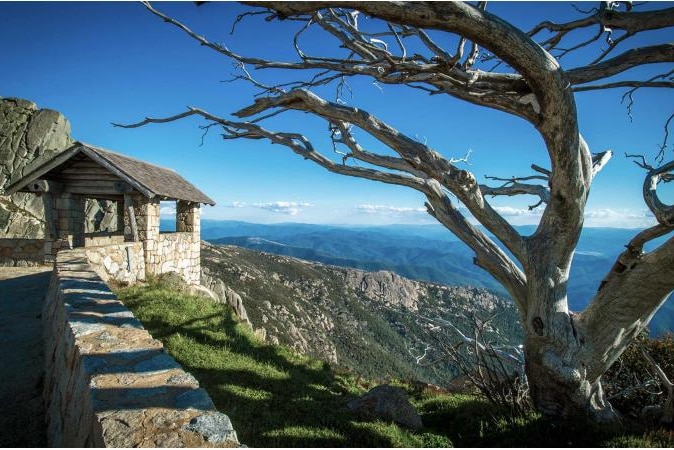 A tree and rudimentary stone shelter in the foreground to an enormous valley.