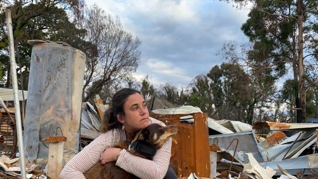 Jess hugs her dog in front of the rubble of her former home.