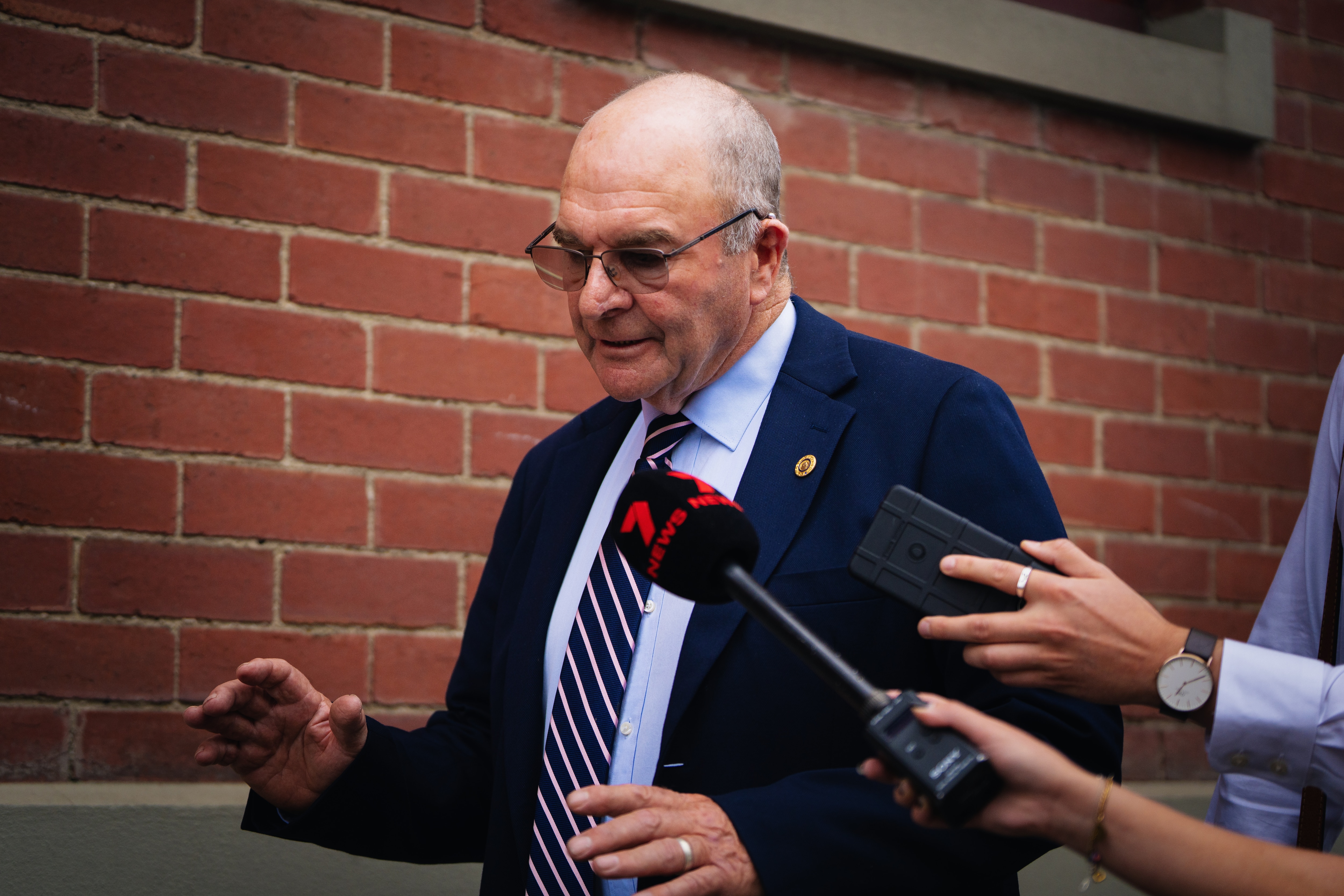 Um homem andando com microfones próximos ao rosto.