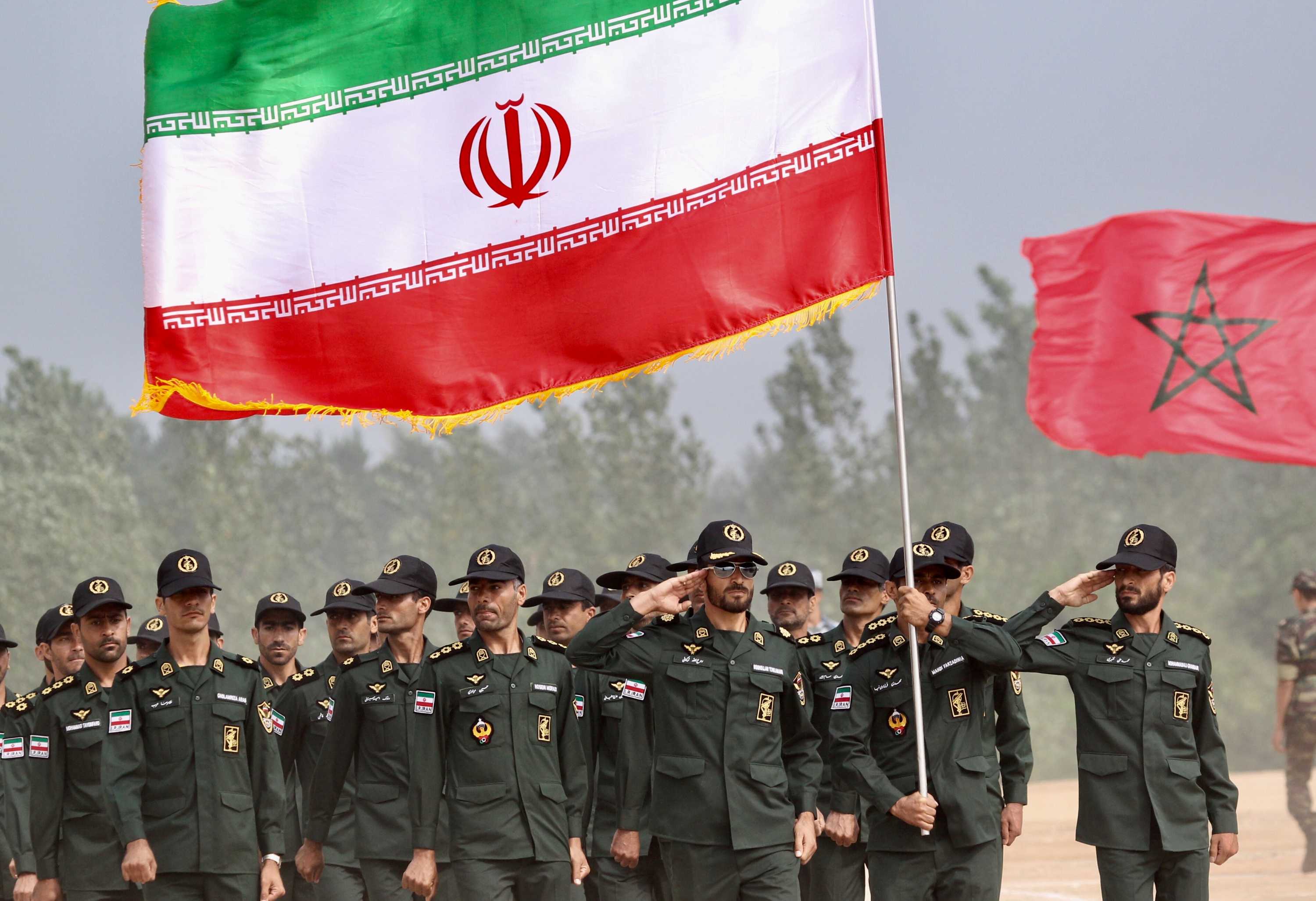 成排的​​伊朗军人在一面巨大的伊朗国旗下站岗。
