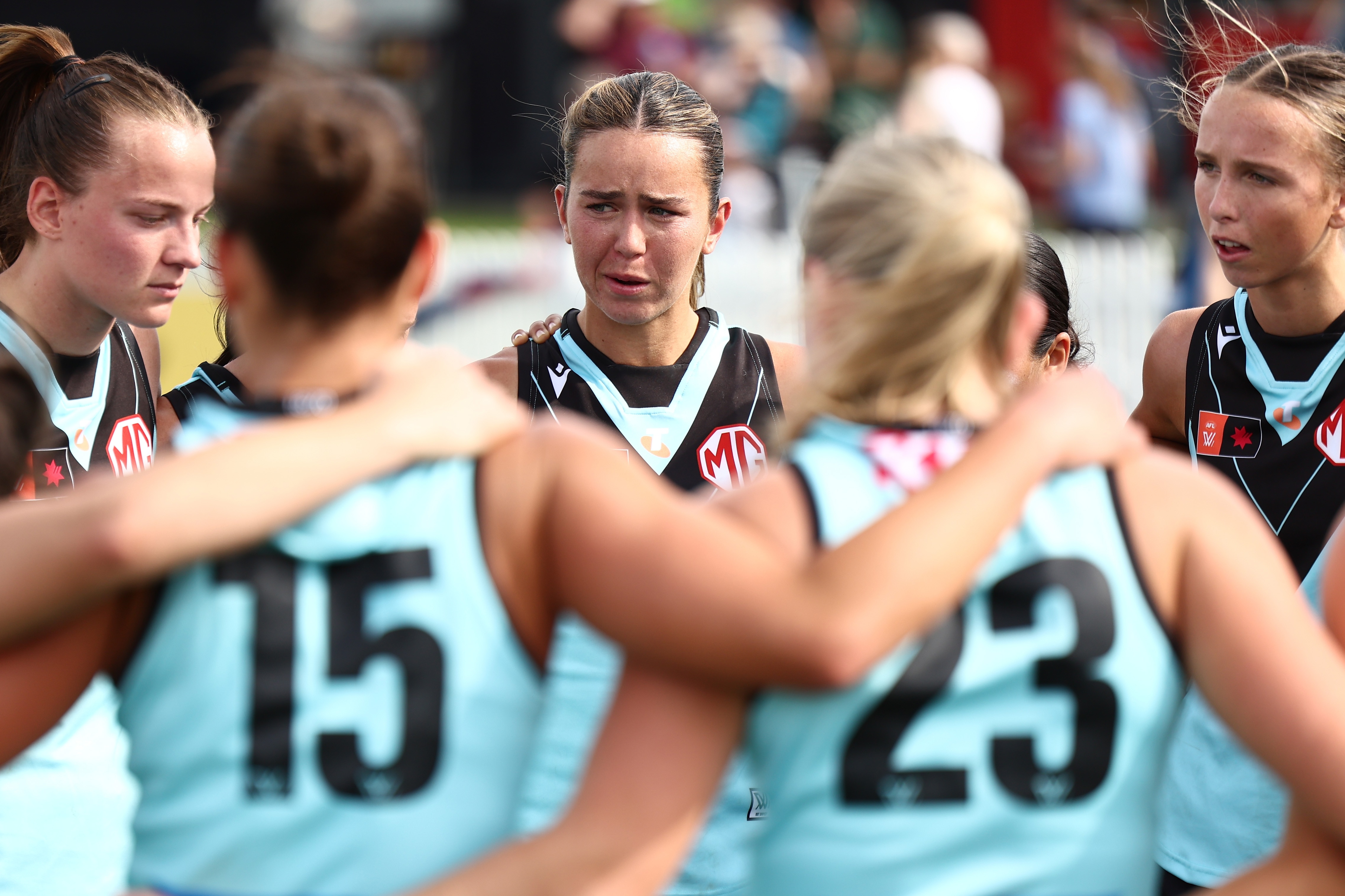 Ella Heads in a huddle with Port Adelaide AFLW players.