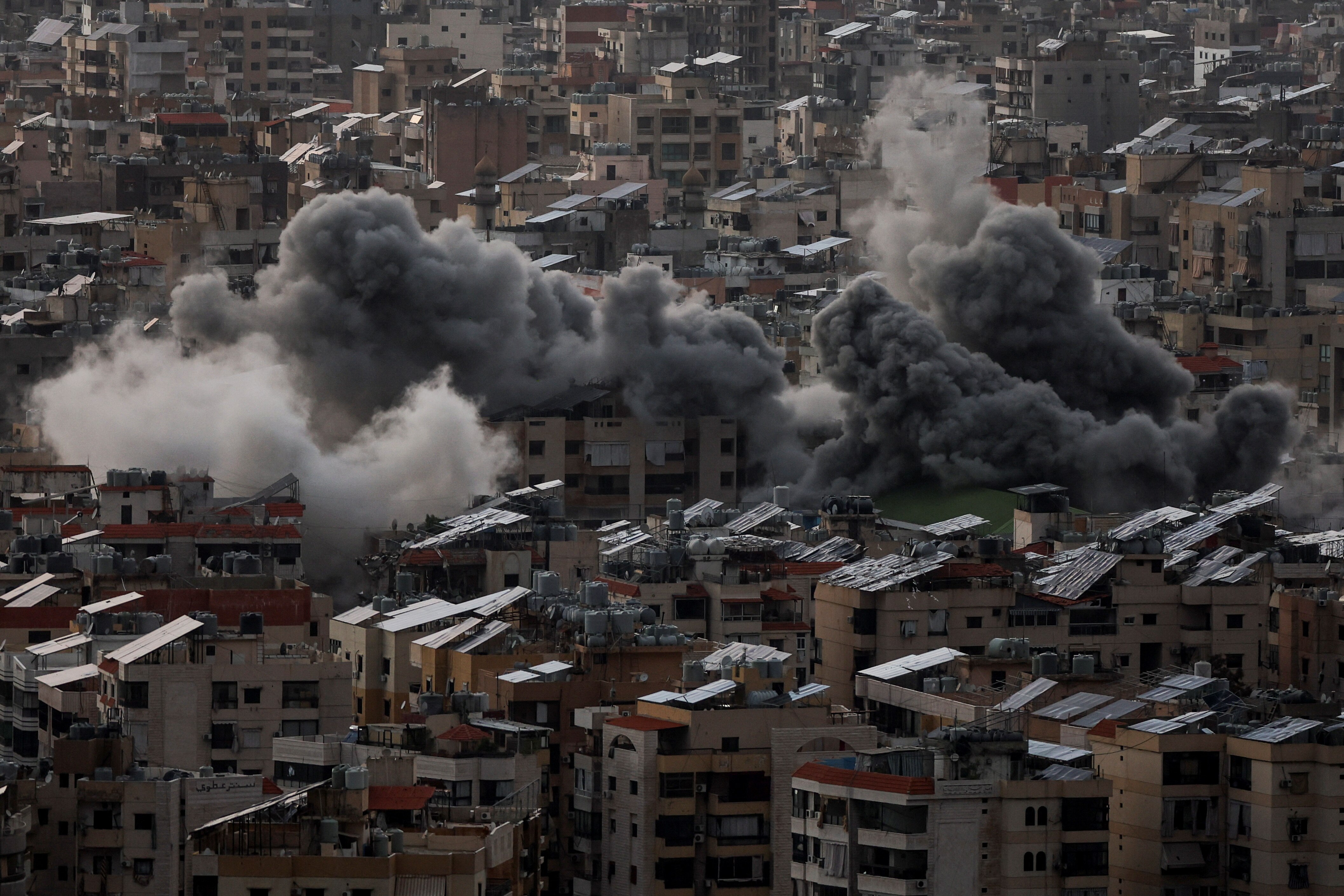 Smoke plumes rising from a dense residential area of apartment buildings in Beirut.