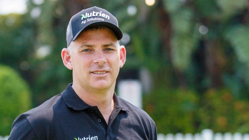 A man, wearing a black shirt and cap with the wording Nutrien Ag Solutions written on both